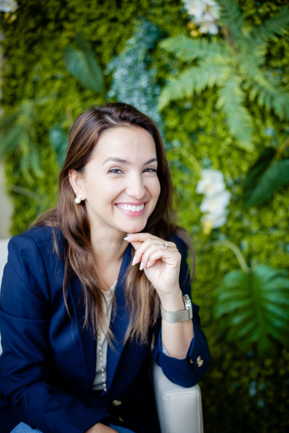 Isadora Castilho sorrindo, psicóloga e neuropsicóloga, diante de um jardim vertical